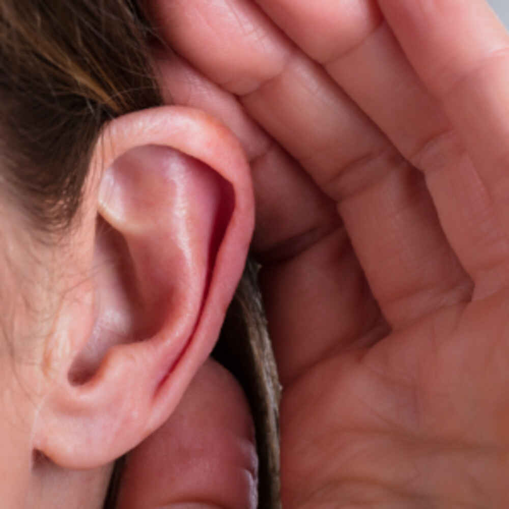 Woman holding hand to ears to hear