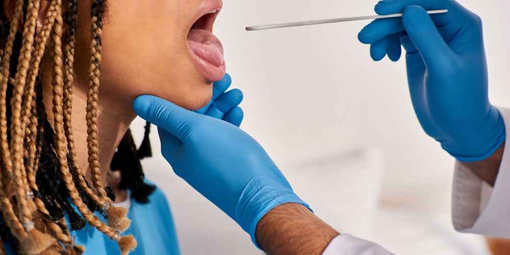 ENT doctor checking pediatric patient's tonsils and adenoids